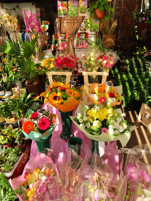 A vibrant display of fresh flower bouquets arranged on a table in a floral shop, with an assortment of colorful blooms including pink, yellow, orange, and white flowers, wrapped in wrapping paper and